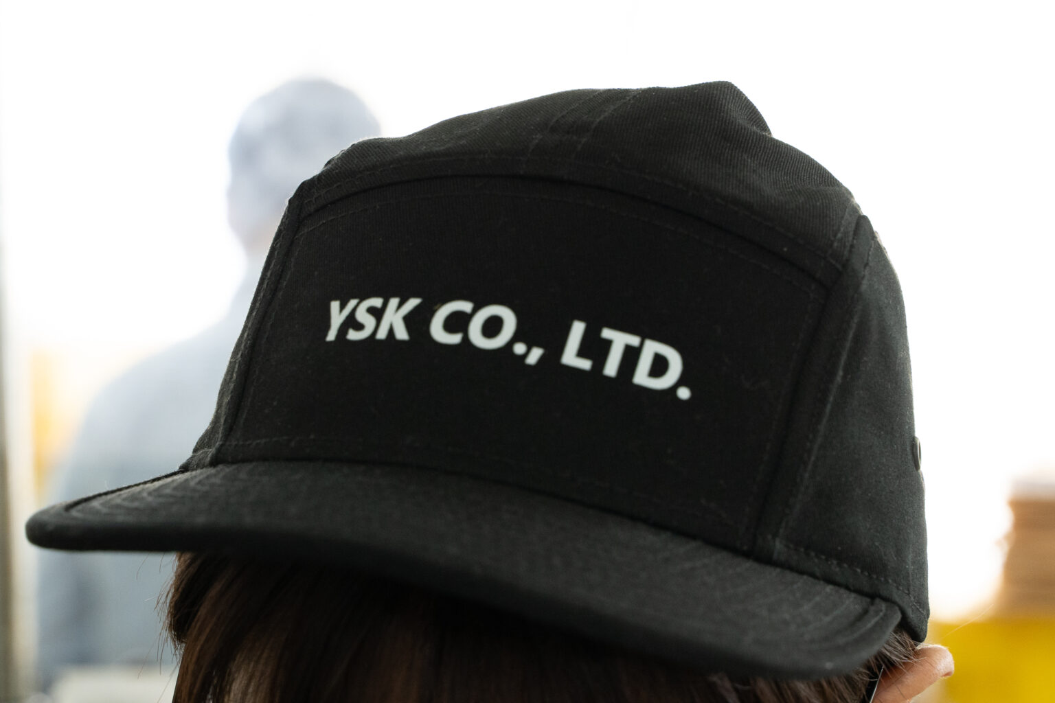 YSKのロゴ入りキャップをかぶったスタッフの後ろ姿